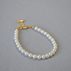 Gros plan d'un élégant bracelet en perles blanches avec fermoir doré et extension