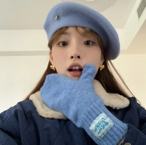 Close-up of light blue wool beret and knitted mittens set with heart earrings