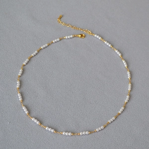 Détail du collier en chaîne dorée avec perles blanches et fermoir mousqueton robuste