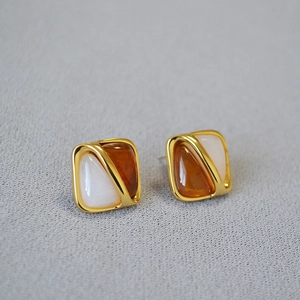 Macro shot of geometric brass studs featuring amber and cream bicolor resin inlay
