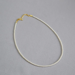 Détail d'un collier de perles élégant avec fermoir mousqueton doré et chaîne réglable