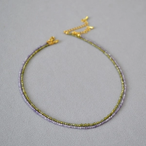 Détail d'un collier double couche avec pierres violettes et vertes et fermoir doré
