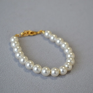 Vue détaillée d'un élégant bracelet de perles blanches avec fermoir mousqueton doré