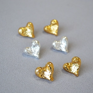 Detailed macro view of irregular textured heart-shaped gold and silver plated earrings