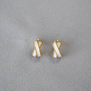 Detailed view of criss-cross enamel earrings with golden beaded edges and silver posts