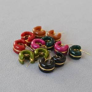 Group shot of colorful C-shaped hoop earrings with gold-line accent on grey fabric