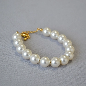 Gros plan détaillé de perles blanches sur un bracelet avec fermoir mousqueton doré