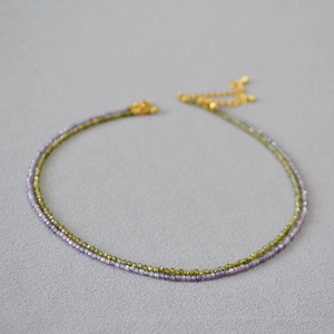 Gros plan sur un collier double couche avec des perles facettées violettes et vertes