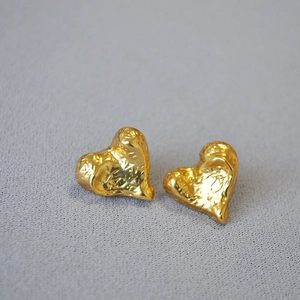 Macro shot of gold heart earrings featuring unique hammered texture and vintage finish