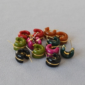 Macro shot of colorful enamel C-shape hoop earrings with central gold line details