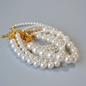 Détail de bracelets en perles multicouches avec fermoirs mousquetons dorés et chaînettes