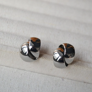 Macro view of polished silver knot stud earrings in a minimalist jewelry display box