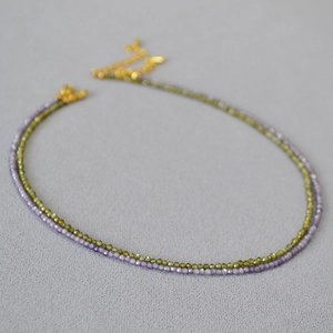 Détail des colliers de perles facettées violettes et vert olive avec chaîne d'extension