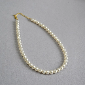 Détail d'un collier de perles élégant avec fermoir homard doré et chaîne d'extension réglable
