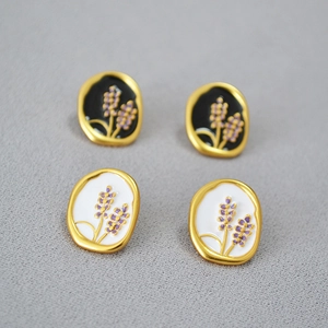 Close-up of handmade lavender enamel stud earrings in black and white oval designs