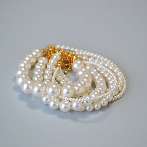 Détail d'un ensemble de bracelets en perles de tailles variées avec fermoir doré