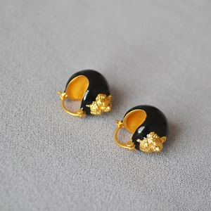 Detail of vintage gold embossed lion head motif on black enamel hoop earrings