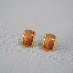 Macro shot of rectangular gold earrings with brown marble texture enamel inlay