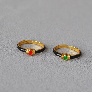 Detail of vintage French gold rings with black enamel, red and green oval gemstones