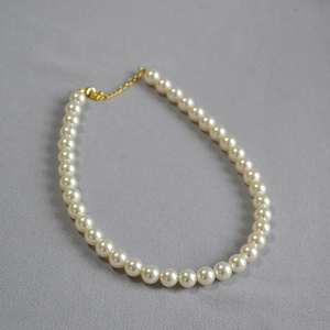 Détail d'un collier de perles blanches avec fermoir mousqueton doré et chaîne d'extension