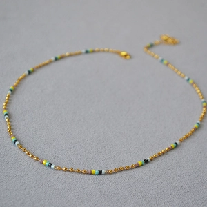 Détail macro de perles colorées et fermoir doré sur un collier ras du cou délicat