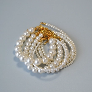 Détails de bracelets élégants en perles blanches de tailles variées avec fermoirs dorés