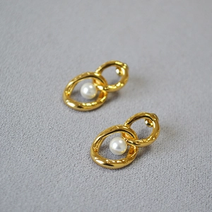 Makroaufnahme goldener gehämmerter Doppelring-Ohrringe mit eleganter Perlenteil
