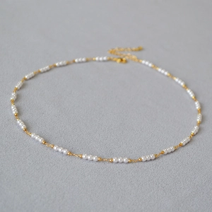 Détail d'un collier plaqué or minimaliste avec petites perles et fermoir mousqueton