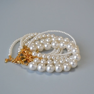 Détail de bracelets en perles blanc crème de tailles variées avec fermoirs dorés