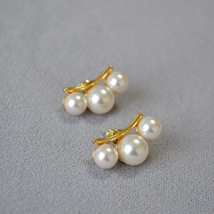 Détail de boucles d'oreilles en laiton doré avec trois perles blanches dégradées
