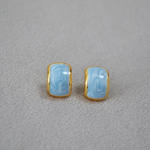 Detail of vintage geometric brass earrings with light blue marble enamel finish