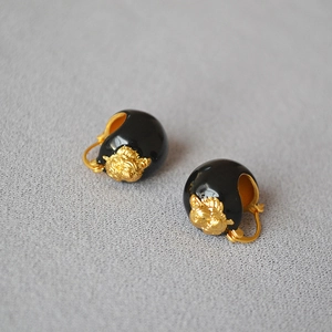 Close-up of vintage gold tiger head relief on black enamel hoop earrings for women