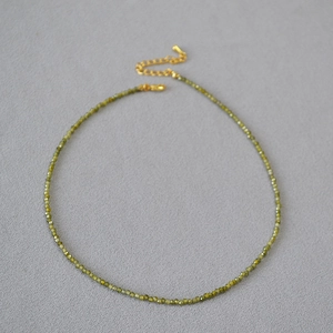Détail d'un collier de fines perles vertes avec fermoir mousqueton doré réglable
