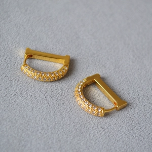 Macro shot of gold-plated D-shaped earrings with micro-pave white cubic zirconia stones