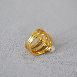Minimalist gold plated multi-layer ring with pearls on a textured grey background
