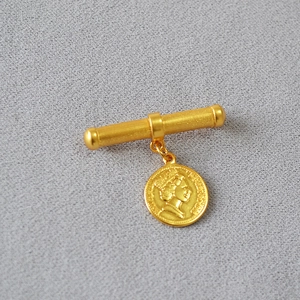 Macro detail of gold-plated queen coin pendant and textured bar on vintage French brooch
