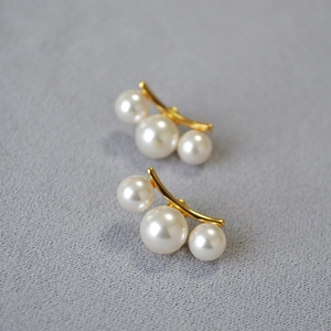 Détail de boucles d'oreilles minimalistes en laiton doré avec trois perles en arc