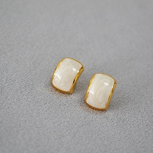 Macro view of vintage gold-plated brass earrings with marble texture enamel inlay