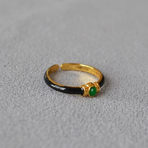 Detail of vintage gold-plated ring featuring black enamel and a green oval gemstone