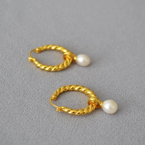 Gros plan détaillé des boucles d'oreilles en laiton doré avec perles blanches élégantes