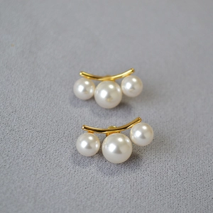 Vue détaillée des boucles d'oreilles dorées avec trois perles d'imitation symétriques