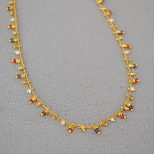 Detailed shot of gold beaded necklace with colorful beads on textured fabric