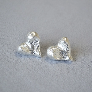 Macro detail of silver irregular textured heart earrings with an organic hammered finish