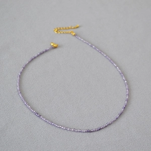 Détail macro d'un collier de fines perles d'améthyste violette avec chaîne dorée réglable
