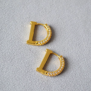 Gold plated D-shape earrings with zircon micro-paving on grey frosted background