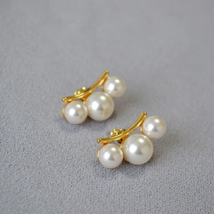 Vue détaillée de trois perles brillantes sur des boucles d'oreilles en laiton doré