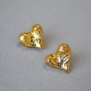 Close-up of vintage heart earrings with irregular crushed texture and gold finish