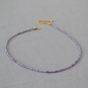 Vue détaillée des perles violettes facettées et du fermoir doré de ce collier délicat