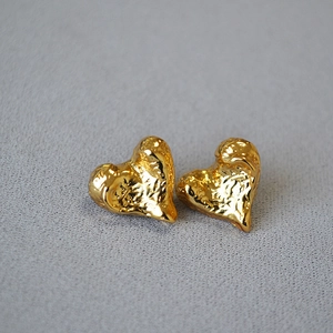 Macro shot of gold-plated heart studs featuring irregular hammered lava textures