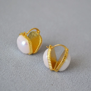 Détail de boucles d'oreilles créoles cœur avec incrustation perle et doré texturé